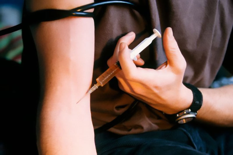 Injecting heroin with a needle photo