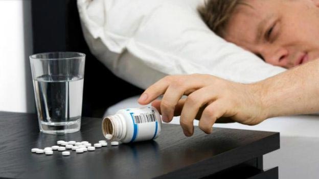 image showing a man reaching for sleeping pills